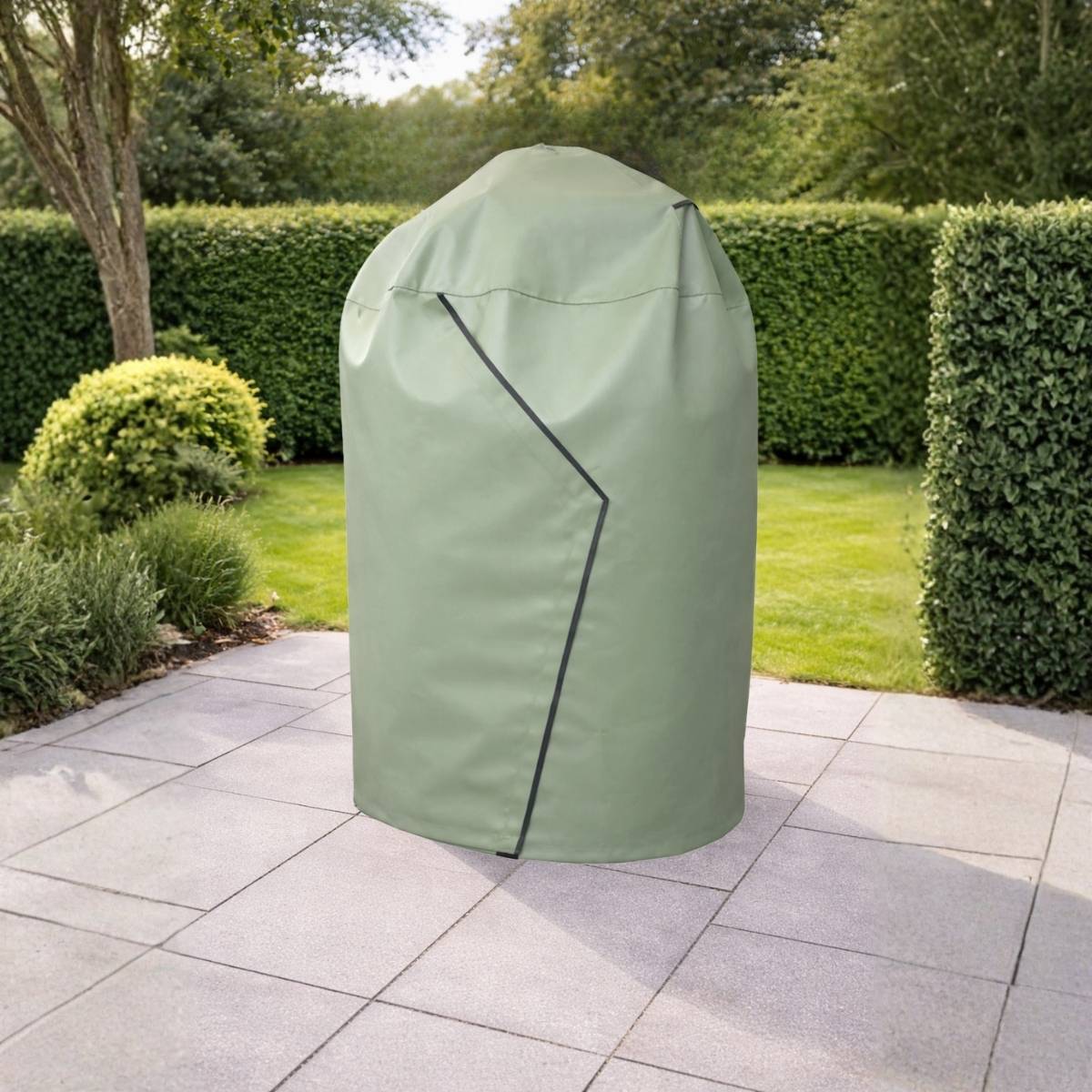 Clarijs BBQ hoes in de kleur mat olive over een kamado barbecue van The Bastard in een tuinsetting. Duurzame PVC beschermhoes die je barbecue beschermt tegen regen en vuil.